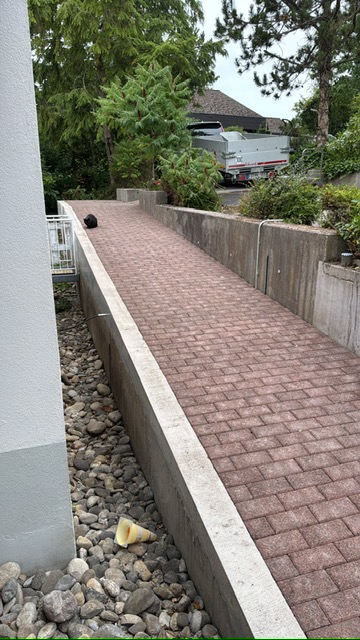 Von Werkliebe gepflasterter barrierefreier Weg entlang eines Gebäudes